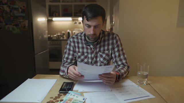 Financial problems. Sad man trying to find solution to taxes and debts at home in kitchen. Brainstorming ways of solving money troubles. Stressed male calculates costs, try to keep money in savings. 