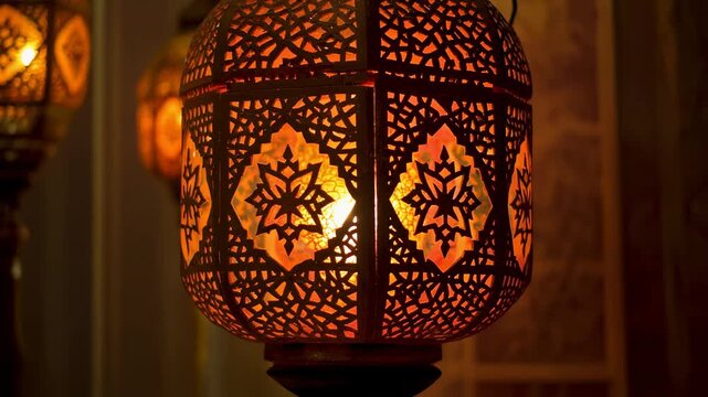 Close up of a beautifully designed, ornate metal lantern glowing with warm light, casting intricate patterns and creating a cozy, atmospheric ambiance.
