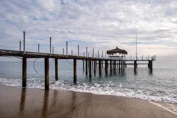 Fototapeta premium Old Pier Standing Over Calm Sea Water. Abandoned Pier Over the Sea. Deserted Wooden Pier in Seascape. Lonely Abandoned Dock Extending into the Ocean.