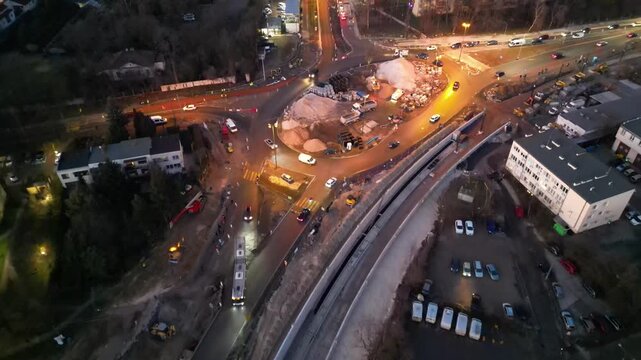 Aerial view of busy construction site at night, showcasing vehicles and machinery in action, with dynamic camera movement capturing scene evolution and urban development
