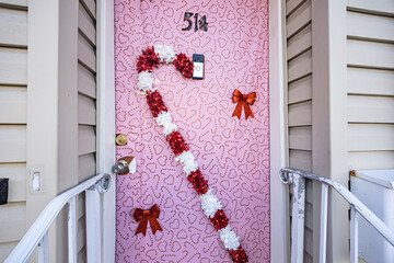 Pink front door decorated with heart pattern and festive red and white garland for valentine's day.