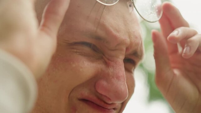 white man rubbing eyes after rain, removing round glasses with drenched lenses, closeup reaction on cloudy path, squinting forehead, candid emotional moment, traveler wiping face, vulnerability