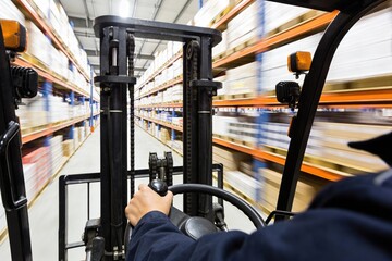 Operator's view from a forklift moving through a warehouse, carrying goods on shelves