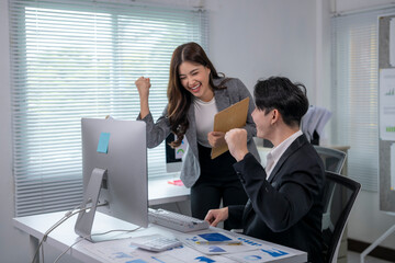 Business people celebrating success while working on desktop computer