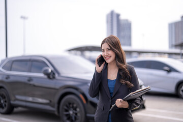 Young businesswoman talking cellphone standing parking lot