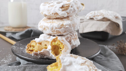 Stack of Glazed Powdered Donuts with Milk on a Bright Table
