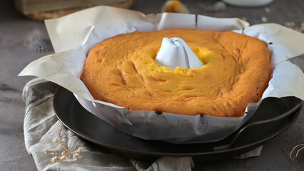 Homemade Sponge Cake in Parchment Paper on Rustic Table