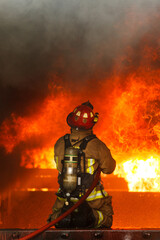 Fototapeta premium Firefighter facing intense fire during emergency response operation