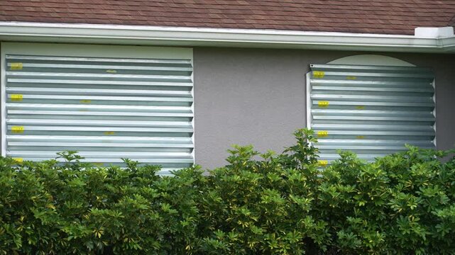 Boarded up windows with steel storm shutters for hurricane protection of residential house. Protective measures before natural disaster in Florida