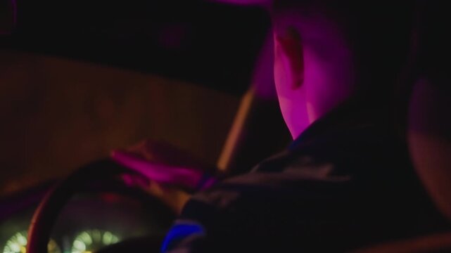 Side profile driver under neon light, checking lane and rearview while steering through quiet urban streets rideshare operator vibe with moody purple wash, shallow depth of field and reflective