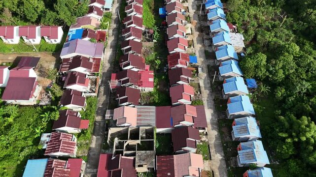 The view from above shows rows of houses with rusty roofs, surrounded by shady trees and narrow streets.