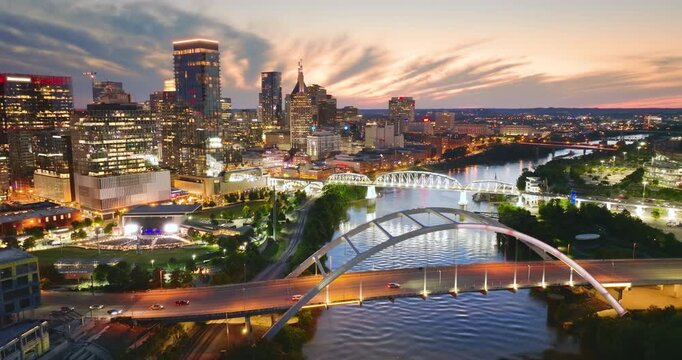 Driving cars on bridge highway near high-rise buildings in downtown district of Nashville, Tennessee, USA. American city with business financial district at sunset.