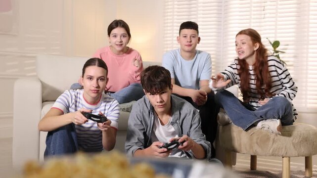 Teenagers playing video game on sofa at home