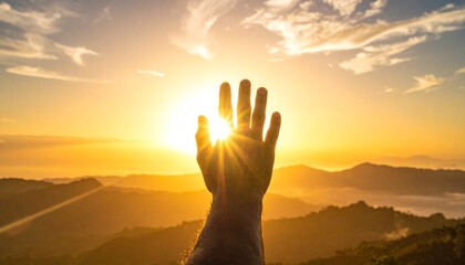 Human hand reaching out, blocking the golden sun at sunrise or sunset over scenic mountain landscape, symbolizing hope and freedom.