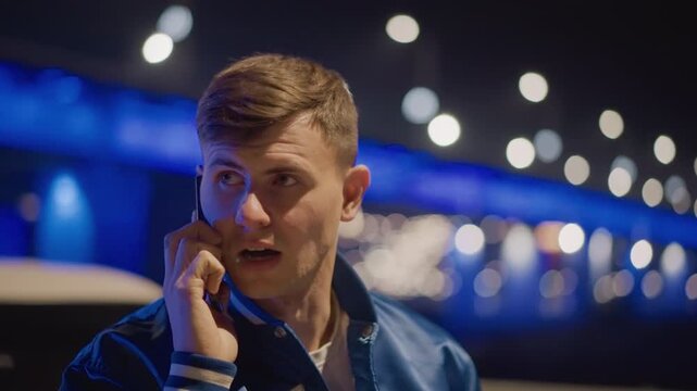 caucasian man on phone by car, latenight driver receiving urgent call, street racer calling backup, mechanic arranging tow, friend coordinating pickup blue neon bridge lights, reflective car panels,