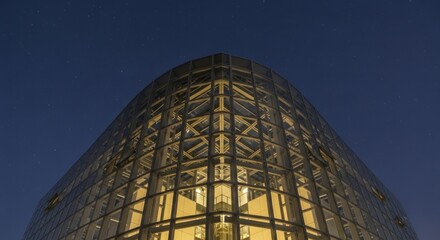 Illuminated contemporary glass structure rises against a dark night sky scattered with stars