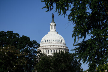 United States Capitol building with iconic dome and American flag under clear blue sky in...