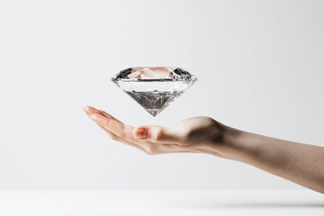 A hand holds a sparkling diamond, elegantly displayed, creating an impression of luxury and beauty against a minimalistic background.