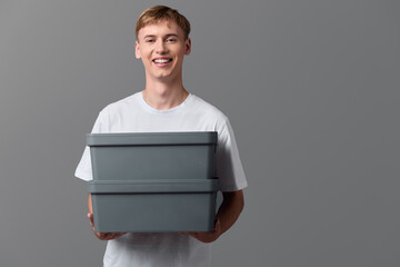 Smiling delivery handler holding stacked boxes for shipment, casual attire and friendly service, concept of packaging and order fulfillment, logistics and courier workflow