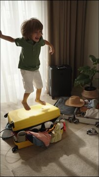 Joyful child jumping on packed suitcase during family travel preparation playful weekend getaway seaside vibes energetic childhood moment warm home light positive lifestyle scene summer adventure mood