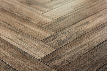 A closeup, low-angle shot of interior hardwood flooring laid in a classic, diagonal herringbone...