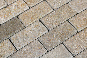 Full-frame closeup of an outdoor pavement surface made from rectangular pavers in a diagonal running bond pattern.