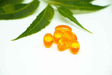 Medical concept of vitamin e capsules isolated on white background with some leafs