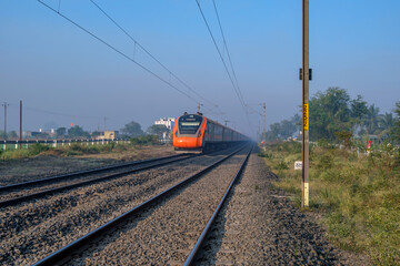Saffron coloured Vande Bharat Express near Pune India. This is a made in India train set and also known as Train 18.