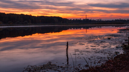 Beautiful summer sunset and colorful sky over the lake. Clouds are reflected in the calm water. Beauty in this world