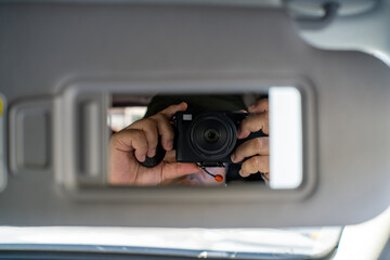 Reflection of Hands Holding Camera in Vehicle Mirror