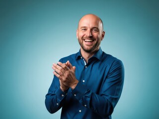 Smiling man in blue shirt clapping hands happily on blue background