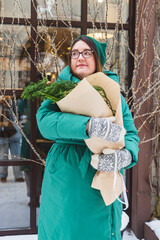A girl holds a bouquet with coniferous branches