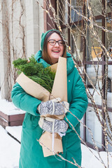A girl holds a bouquet with coniferous branches