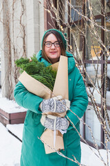 A girl holds a bouquet with coniferous branches