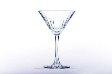 Empty martini glass on glass shelf on white background.