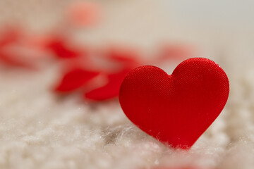 Small red fabric hearts scattered on the soft white surface create a romantic atmosphere, perfect for digital Valentine's Day content.