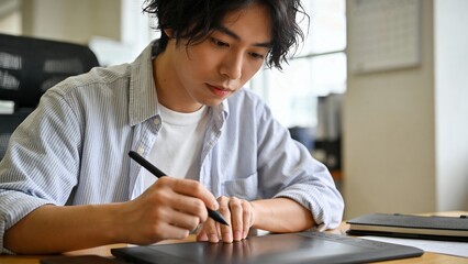 デスクでペンタブレットを使い作業する男性クリエイター