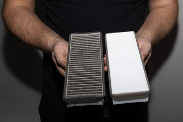 Man holding a dirty and a new air purifier filter during home filter replacement.