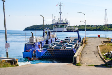 car ferry arriving at  ramp with full deck of vehicles:  this small open roll on roll off boat serves Brier Island an Island  in Nova Scotia, shot in summer time room for text