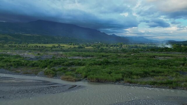 A rising aerial from the Chico River reveals distant mountain ranges and scattered rice field patches Bontoc, Nueva Vizcaya, Philippines