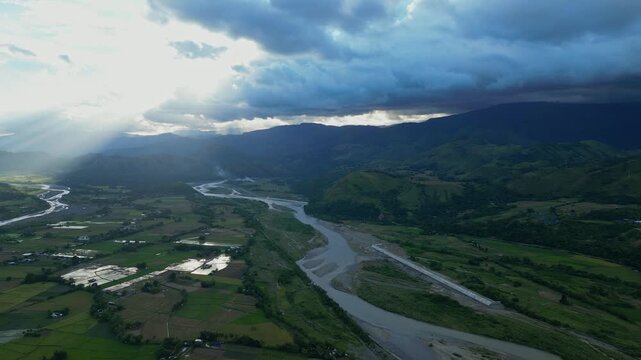 A wide pan of the Chico River reveals braided channels, shaded mountains, and sunbeams piercing cloud cover Bontoc, Nueva Vizcaya, Philippines