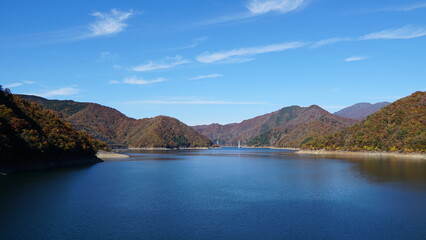 Naklejka premium Autumn Colors at Tokuyama Dam and Lake, Gifu – Reflections of Nature and Engineering Harmony