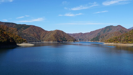 Fototapeta premium Autumn Colors at Tokuyama Dam and Lake, Gifu – Reflections of Nature and Engineering Harmony