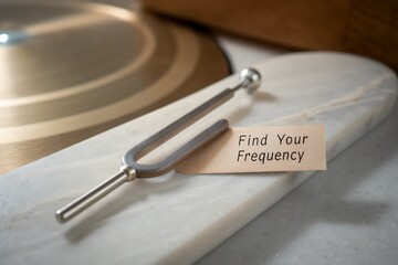 Tuning fork rests on marble with message Find Your Frequency