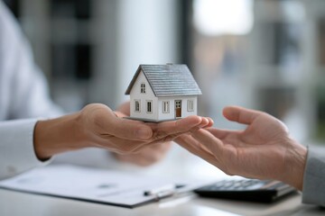 real estate agent holding house model and giving it to custome