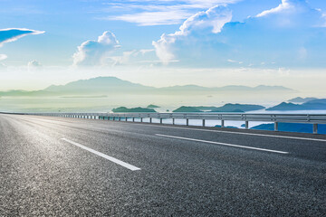 Fototapeta premium Empty asphalt road and blue sea with mountain natural landscape under blue sky