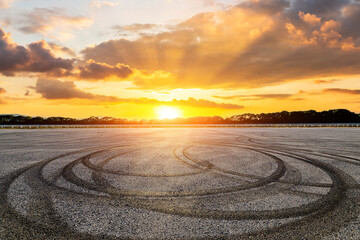 Empty asphalt race track road with tire tracks and beautiful sky clouds at sunset © ABCDstock