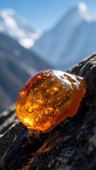 mountain landscape in, Dark brown Shilajit resin oozes from cracks in rugged Himalayan rock surface. Golden undertones glisten on the earthy mineral deposit. Majestic snowy mountains rise in backgroun