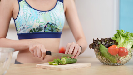 Meal Preparation. Woman slicing cucumber for healthy meal, promoting cooking skills.
