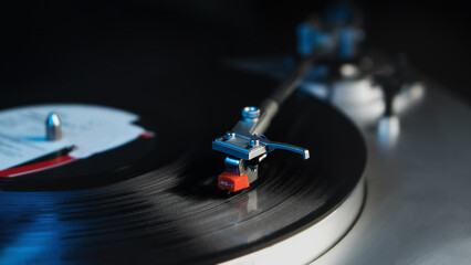 Close-up of vintage turntable spinning vinyl record with needle arm in dim lighting